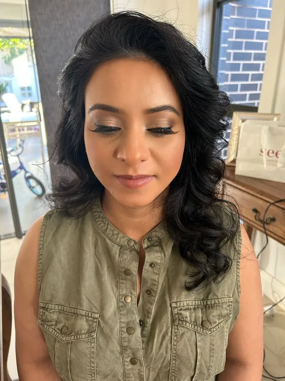 Bronze shimmer eyeshadow with winged lashes and a muted pink lip, worn with long curls